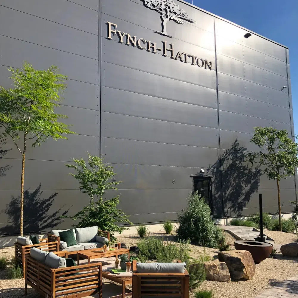 The FYNCH-HATTON headquarters building in Mönchengladbach with its tree logo signage above a landscaped outdoor lounge terrace.